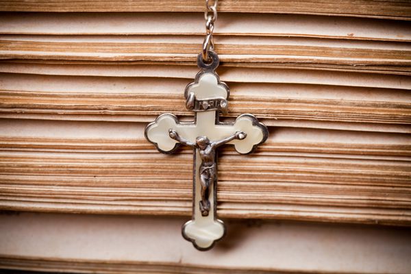 صلیب با عیسی آویزان در دو طرف کتاب مقدس باز شده نمای نزدیک