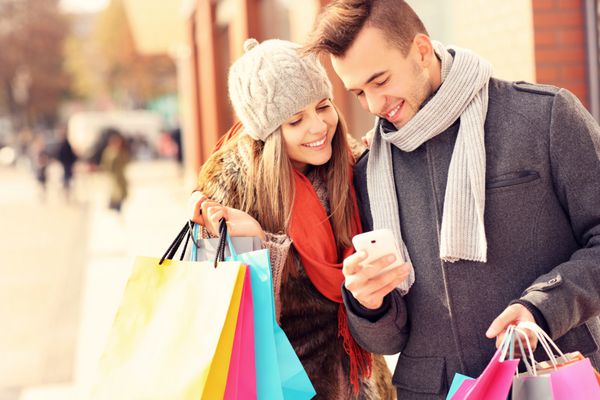 تصویری از خرید یک زوج با گوشی هوشمند در شهر
