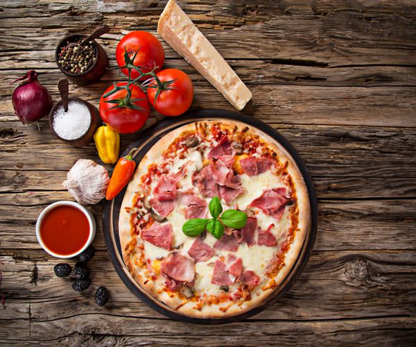 پیتزای خوشمزه ایتالیایی که روی میز چوبی سرو می شود نمای نزدیک