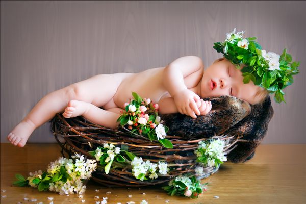 نوزاد تازه متولد شده در لانه ای با تاج گل روی سرش می خوابد