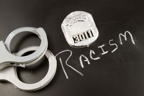 کلمه نژادپرستی روی تخته سیاه با نشان پلیس و دستبند