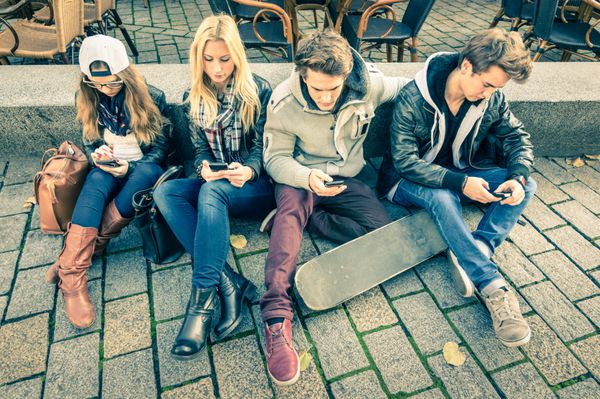 گروهی از دوستان هیپستر جوان با گوشی هوشمند با بی علاقگی نسبت به یکدیگر - وضعیت مدرن تعامل فناوری در سبک زندگی بیگانه - اتصال به اینترنت وای فای