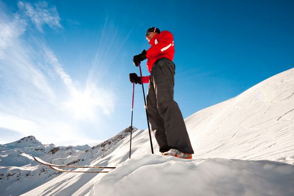 مرد جوانی در بالای کوه آماده برای اسکی