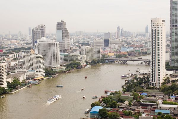 کشتی با نمای بالا در رودخانه چائو فرایا پل و منظره شهری در بانکوک تایلند
