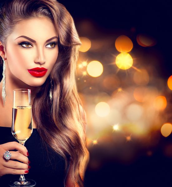 دختر مدل با لیوان شامپاین در مهمانی در حال نوشیدن شامپاین در پس زمینه درخشان تعطیلات زن زیبایی با آرایش مد کامل جشن کریسمس و سال نو
