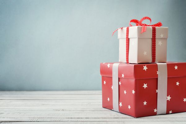 جعبه های هدیه با روبان و دکور کریسمس در زمینه چوبی