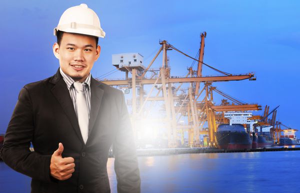 مرد مدیر جوان ایستاده و امضا می کند کنترل کیفیت صادرات واردات کشتی بندری و خدمات صنعت لجستیک در برابر کشتی در اسکله کشتی های تجاری