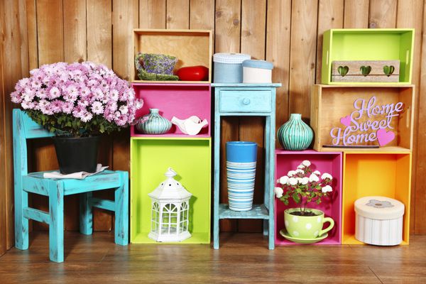 قفسه های رنگارنگ زیبا با اشیاء مختلف مربوط به خانه در زمینه دیوار چوبی