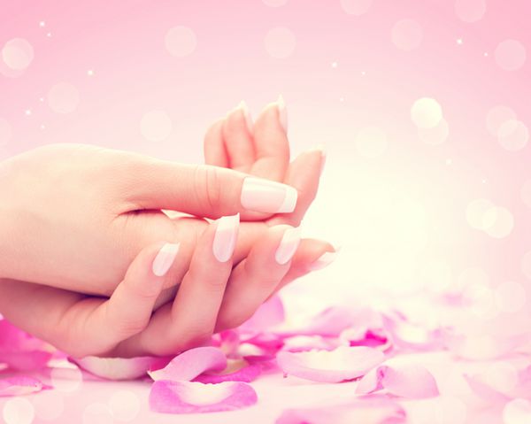 مانیکور آبگرم دست‌ها دست‌های زنانه زیبا پوست نرم ناخن‌های زیبا با گلبرگ‌های گل رز صورتی دست های زن سالم سالن زیبایی درمان زیبایی ناخن های زیبا با مانیکور فرانسوی