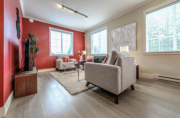 سوئیت نشیمن لوکس مدرن با دیوارهای رنگ قرمز اتاق با مبل و صندلی و به زیبایی با میز قهوه گلدان تزئین شده است طراحی داخلی یک خانه کاملا جدید