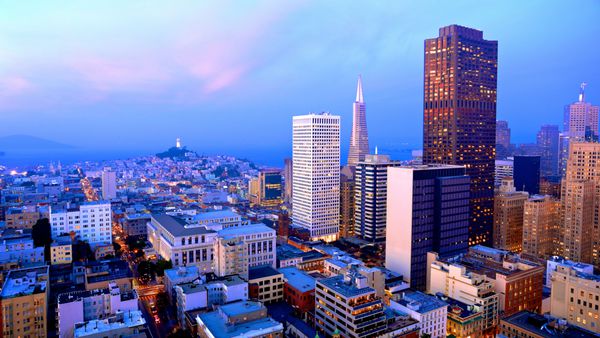 منظره شهری سان فرانسیسکو با نمایی از آسمان‌خراش‌های معروف و مکان‌های دیدنی با ابرهای رنگارنگ در غروب