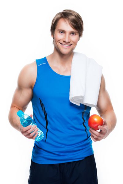 پرتره ورزشکار خوش تیپ با پیراهن آبی آب و سیب را روی پس زمینه سفید نگه می دارد
