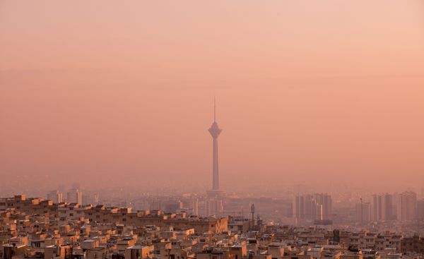 ساختمان های مسکونی روبروی برج میلاد در خط افق آلوده هوای تهران در غروب صورتی