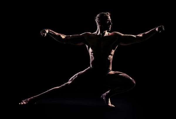 مرد عضلانی ورزشکار که روی پس زمینه سیاه ژست گرفته است زیبایی مردانه پرورش اندام ورزش ها