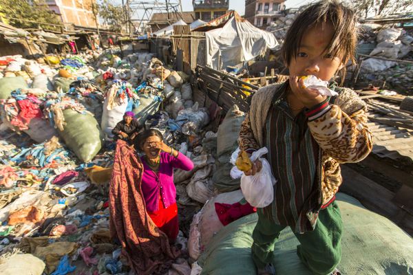 کاتماندو نپال - حدود دسامبر 2013 کودک ناشناس و والدینش در طول ناهار در استراحت بین کار در زباله دانی تنها 35 درصد از جمعیت نپال به سرویس بهداشتی کافی دسترسی دارند