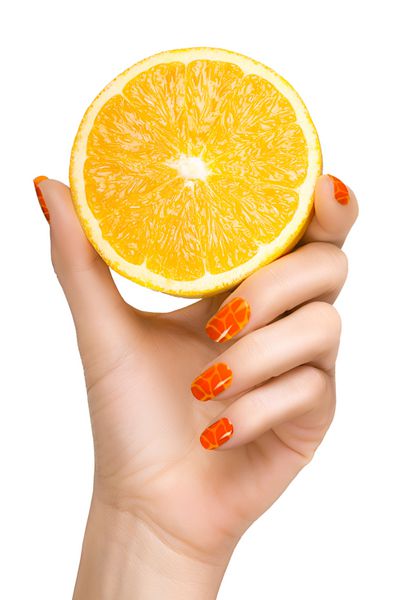 زنی با ناخن های نارنجی مد روز لیمو زرد دلپذیری را در سایه های رنگی متناسب با هنر ناخن و مفهوم غذا در زمینه سفید جدا کرده است