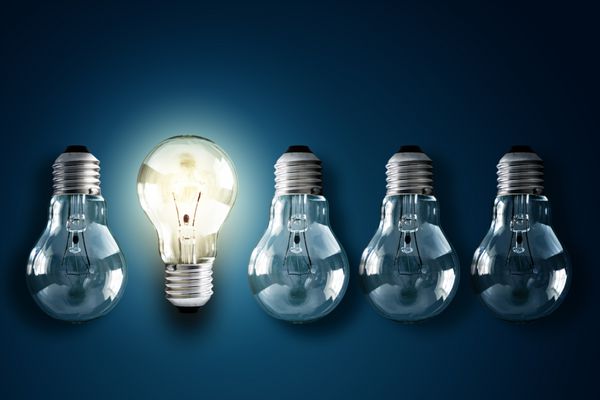 لامپ های روشن در ردیفی از لامپ های کم نور برای خلاقیت نوآوری و راه حل