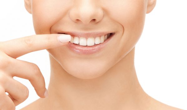 مفهوم سلامت دندان - زن زیبا با اشاره به دندان هایش
