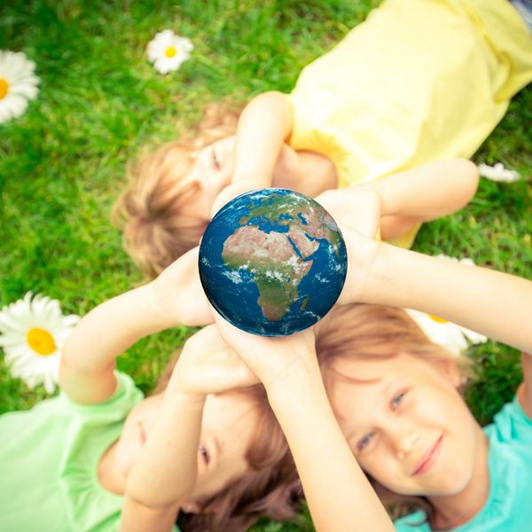 کودکان سیاره سه بعدی را در دستان خود در برابر پس زمینه سبز بهار مفهوم تعطیلات روز زمین عناصر این تصویر ارائه شده توسط ناسا