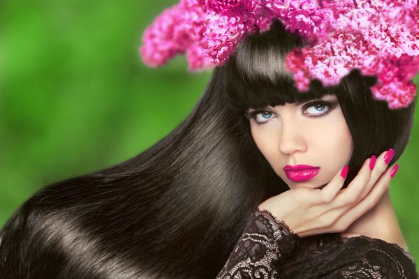 دختر جذاب با موهای بلند گل مدل موی مشکی سالم آرایش ناخن های مانیکور شده زن مدل زیبایی جدا شده در زمینه طبیعی سبز