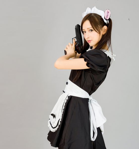 خدمتکار دختر ناز در پس زمینه خاکستری به سبک ژاپنی با تفنگ