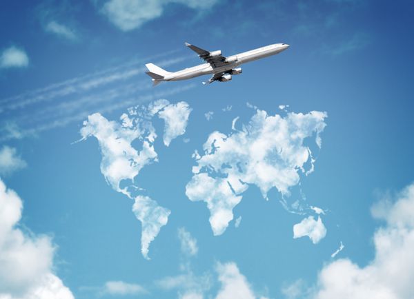 هواپیمای مسافربری در حال پرواز بر فراز آسمان با ابرهایی به شکل مفهوم نقشه جهان برای سفر و تعطیلات