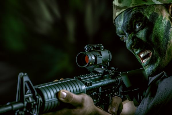 یک سرباز با رنگ جنگی به محدوده تفنگ های خودکار نگاه می کند نظامی جنگی نیروهای ویژه