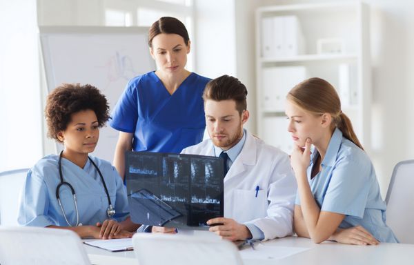 رادیولوژی مردم و مفهوم پزشکی - گروهی از پزشکان که به دنبال تصویر اشعه ایکس در بیمارستان هستند و بحث می کنند