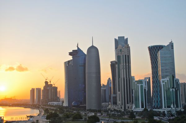 غروب خورشید بر فراز آسمان خراش ها در خط افق مرکز تجاری دوحه پایتخت کشور عربی خلیج فارس قطر