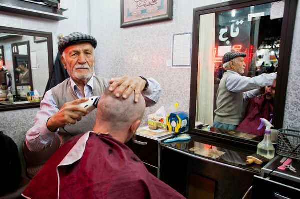 یزد ایران - 20 اکتبر سالمندان در آرایشگاه کوچک در 20 اکتبر 2014 در خاور میانه مشتری را کوتاه و اصلاح می کنند جمعیت یزد نزدیک به 270600 خانوار است