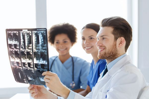 رادیولوژی جراحی مراقبت های بهداشتی مفهوم مردم و پزشکی - گروهی از پزشکان خوشحال که به دنبال تصویر اشعه ایکس ستون فقرات در بیمارستان هستند و در مورد آن بحث می کنند