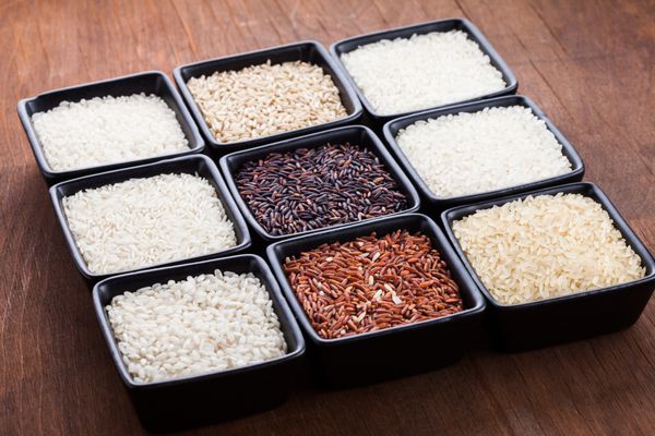 انواع مختلف برنج در کاسه های سیاه جدا شده روی سفید