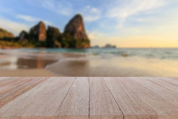 میز چوبی بالا را ببندید و پس زمینه ساحل استوایی را تار کنید