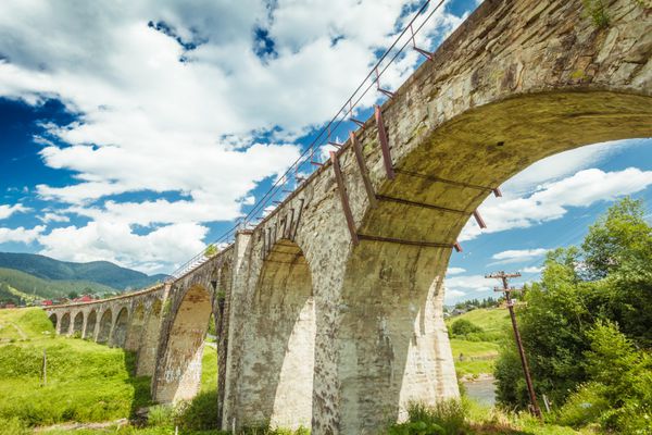 پل سنگی قدیمی در پس زمینه ای از روز تابستانی آسمان آبی