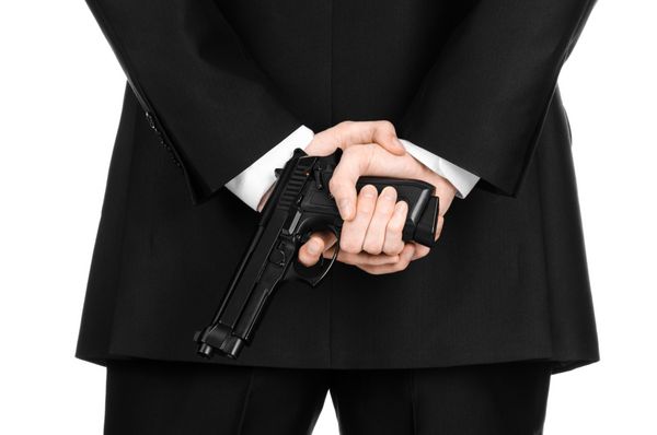 موضوع اسلحه گرم و امنیتی مردی با کت و شلوار مشکی که تفنگی را در پس زمینه سفید جدا شده در استودیو در دست گرفته است