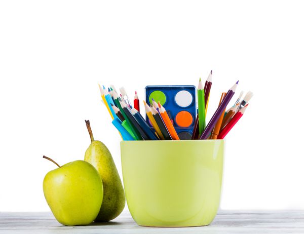 کره سیب و مدادهای جدا شده در پس زمینه سفید بازگشت به مفهوم مدرسه