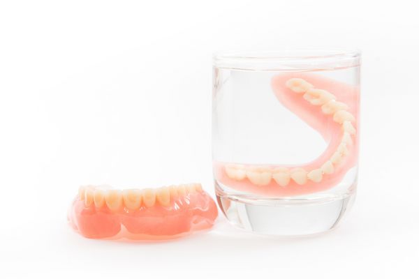 دندان مصنوعی در یک لیوان آب تمیز می شود بهداشت مناسب