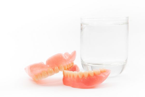 دندان مصنوعی در یک لیوان آب تمیز می شود بهداشت مناسب