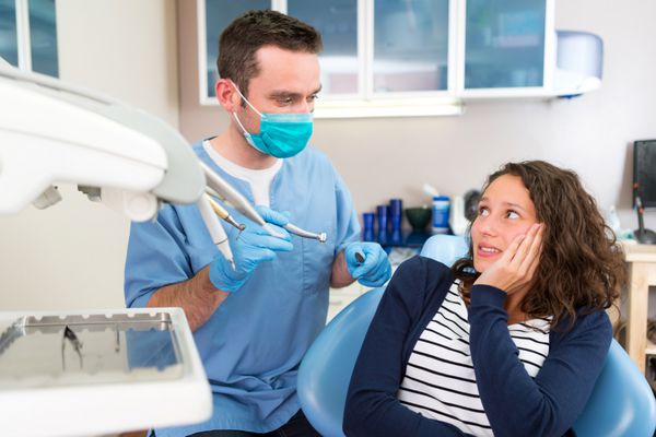 نمایی از زن جوان جذابی که از معالجه شدن توسط دندانپزشک ترسیده است