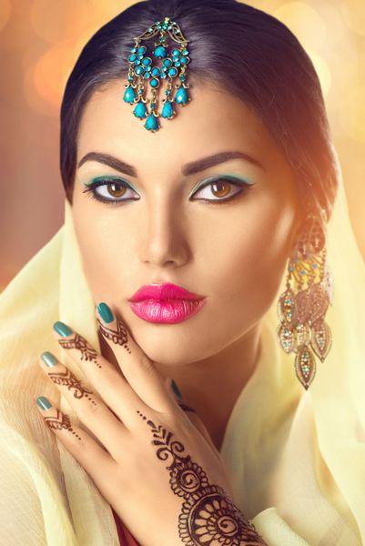 پرتره زن هندی زیبایی دختر مدل هندو با چشمان قهوه ای مهندی روی دست و جواهرات ملی هند که در دوربین نگاه می کنند دختر هندی ساری رسم و رسوم