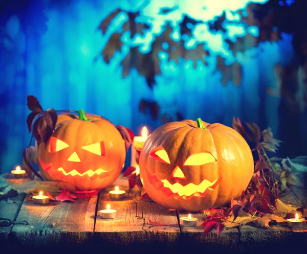 فانوس جک سر کدو تنبل هالووین با شمع های سوزان طراحی هنری تعطیلات هالووین جشن کدو تنبل های هالووین حکاکی شده با شمع های سوزان در جنگل ترسناک عمیق شب