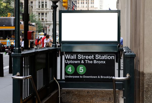 تابلوی تجاری در ایستگاه متروی وال استریت بیلبورد خالی با جمعیت و ترافیک در پس زمینه منطقه مالی منهتن شهر نیویورک