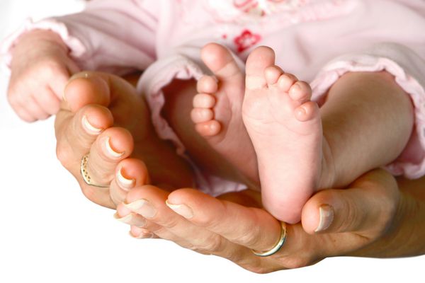 پاهای ریز نوزاد تازه متولد شده با ملایمت در کف دست مادرش جمع شده است