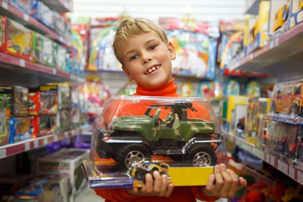 پسر در مغازه با ماشین اسباب بازی در دست