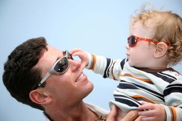 پدر با کودک در عینک آفتابی در پس زمینه آسمان