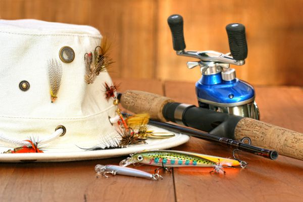 قرقره ماهیگیری با کلاه و طعمه های رنگی روی چوب