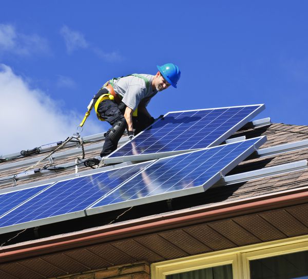 مردی در حال نصب پنل های خورشیدی پوولتائیک انرژی جایگزین روی پشت بام