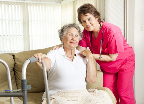 پرستار مهربان از یک زن مسن در خانه سالمندان مراقبت می کند