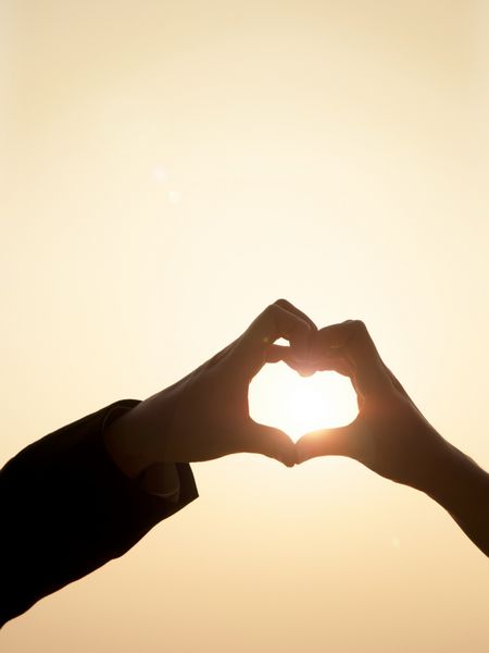 شیلوت دو دست به هم می پیوندند تا شکل قلب را با پرتو خورشید در داخل قلب ایجاد کنند