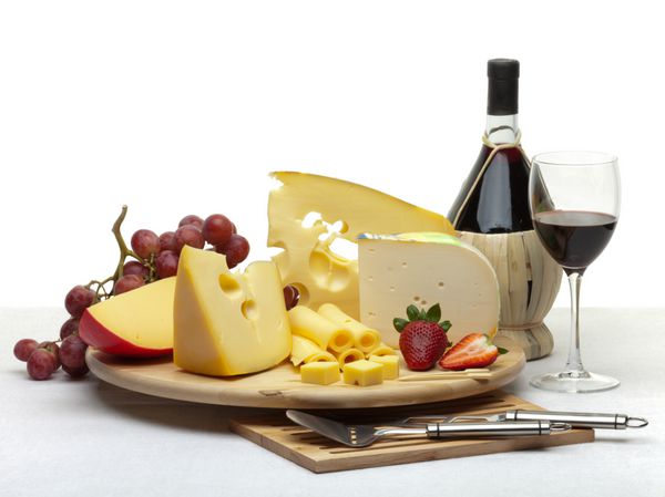 ترکیب پنیر انگور بطری و لیوان و توت فرنگی بر روی یک سینی گرد چوبی روی یک سفره سفید جدا شده در زمینه سفید